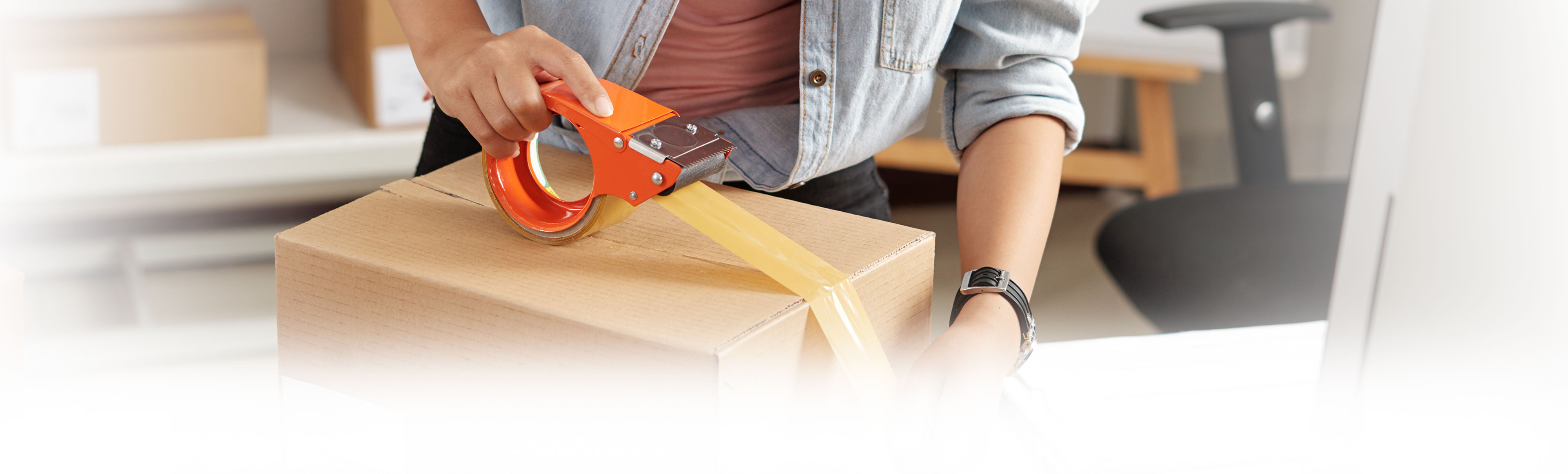 A woman uses packaging tape to prepare a box for shipment