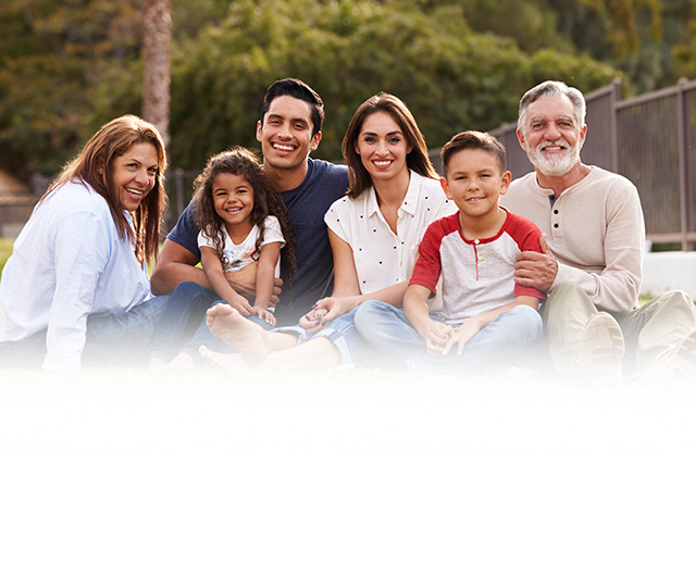 Family sitting on the grass and smiling to the camera