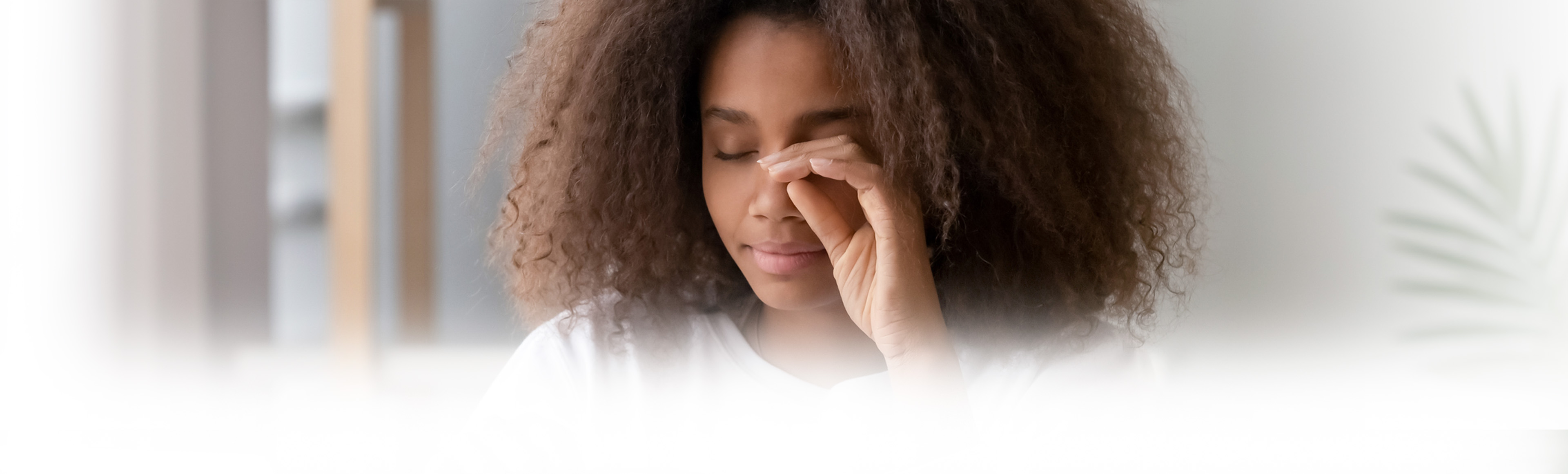Women sitting at a desk, rubbing her eyes