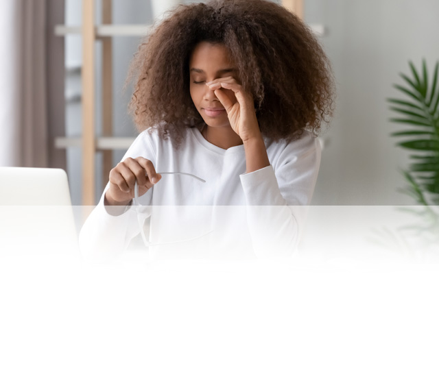 Women sitting at a desk, rubbing her eyes