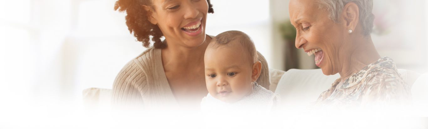 Three generations of women, including an infant, looking at a digital tablet